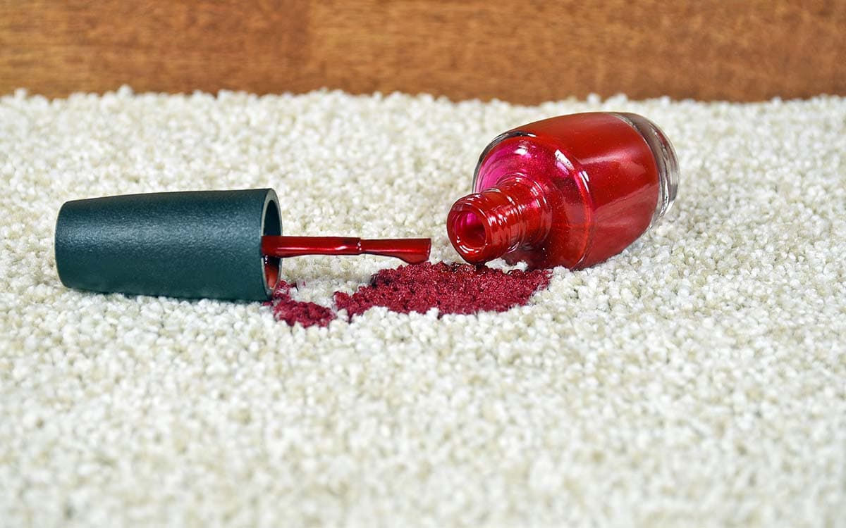 Rød neglelakk sølt på teppe.
