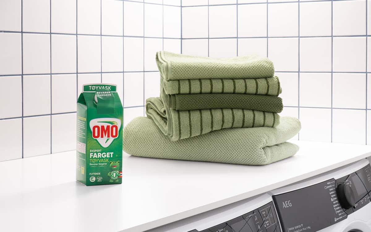 OMO Color foran stabel med brettede håndklær.